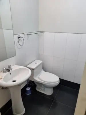 a white bathroom with a toilet and a sink at Departamento acogedor in Abancay