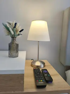 a lamp and a remote control sitting on a table at Habitación Pequeña dentro departamento compartido 402 in Lima