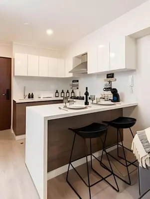a kitchen with white cabinets and two bar stools at Artline Terrace Residence in Lima