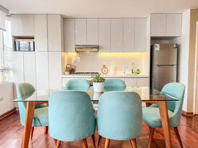 a kitchen with a glass table and blue chairs at LimaViva A in Lima