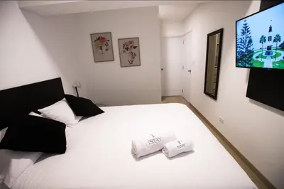 a bedroom with a white bed and a flat screen tv at iStay Atractivo corazón de Miraflores 2 Camas 2 Baños in Lima