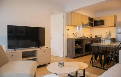 a living room with a large television and a kitchen at Palma Suites by Wynwood House in Lima