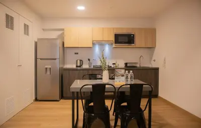 a kitchen with a table with chairs and a refrigerator at Palma Suites by Wynwood House in Lima