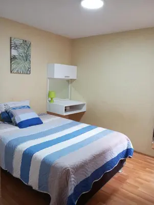 a bedroom with a bed with a blue and white striped blanket at Departamento Condominio Club Carabayllo in Carabayllo