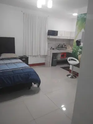 a bedroom with a bed and a kitchen with a table at Habitación acogedora in Lima