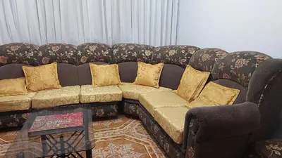 a brown couch with gold pillows in a living room at H&H home in Cusco
