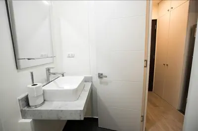 a white bathroom with a sink and a mirror at iStay Encantador Loft Piscina BBQ Gym Bicicleta in Lima