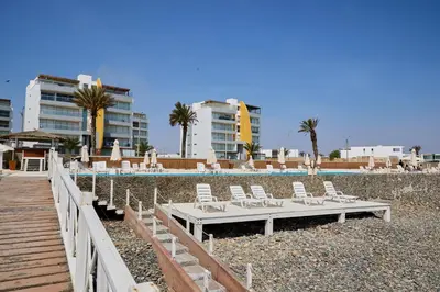a group of lounge chairs and a pool with buildings at PARACAS Sotavento T2 401 in Paracas