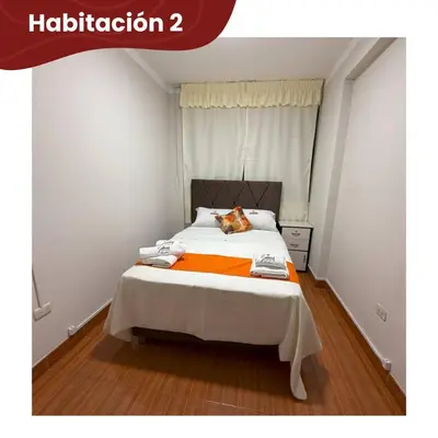 a bedroom with a bed with an orange blanket at Departamentos Sumaq Plaza - Mariscal Cáceres in Ayacucho