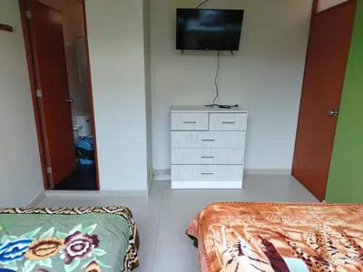a bedroom with a bed and a tv on a wall at Hospedaje el Mirador del Pillcomozo in Huánuco