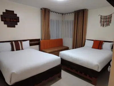 a hotel room with two beds and a chair at Imperium House Cusco in Cusco
