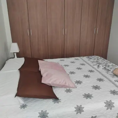 a bed with a pink pillow and wooden cabinets at Elite Apartment in Cusco
