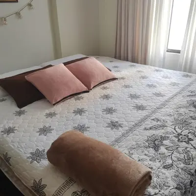 a bed with pink pillows and a blanket on it at Elite Apartment in Cusco