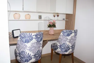 a desk with two chairs and a vase with flowers at Cozy apartment in San Miguel in Lima