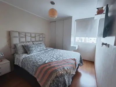 a bedroom with a bed with a comforter and a window at Acogedor departamento con cochera in Lima
