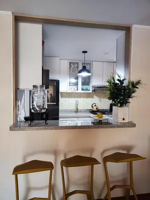 a kitchen with a counter with three stools at Acogedor departamento con cochera in Lima