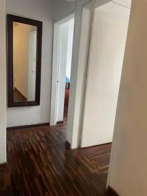 a room with white walls and a mirror and wood floors at Miraflores Dpto 3 dormitorios in Lima