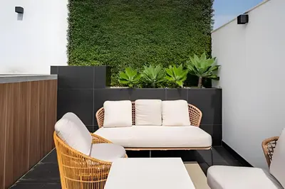 a patio with wicker chairs and a green wall at Edificio The Classic in Lima