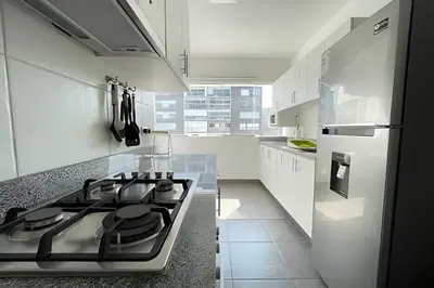 a white kitchen with a stove and a refrigerator at Iconic Miraflores Penthouse 3BR in Lima