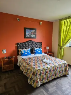 a bedroom with a large bed with an orange wall at Sahara Hotel in Lima
