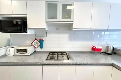 a white kitchen with a stove and a microwave at Modern Apartment between Miraflores & Surquillo in Lima