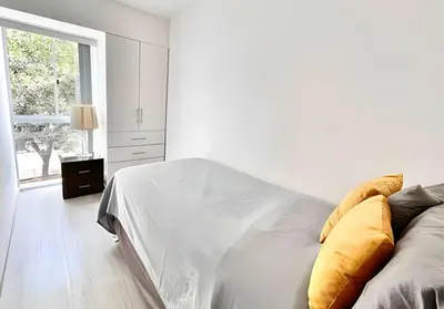 a white bedroom with a bed and a window at Modern Apartment between Miraflores & Surquillo in Lima