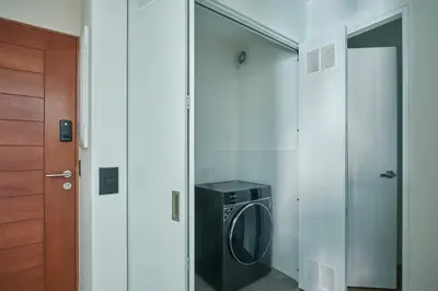 a laundry room with a washer and dryer next to a door at Celestra by Geko in Lima
