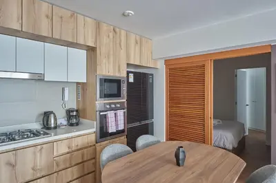 a kitchen with a table and a room with a bed at Celestra by Geko in Lima