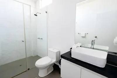 a white bathroom with a toilet and a sink at Mystic Paracas Hotel & Glampings in Paracas