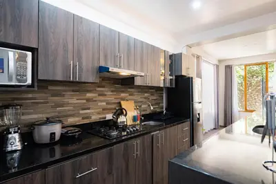 a kitchen with wooden cabinets and a black refrigerator at Rural Retreat with Charming Patio 2 Bedrooms in Urubamba