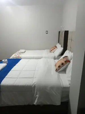 a bedroom with two beds with white sheets at Hotel Sucre in Quinua