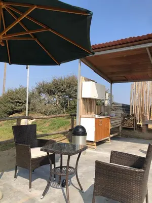 a patio with a table and chairs and an umbrella at Casa de Campo La Martina con piscina y parrilla in Tambo de Mora