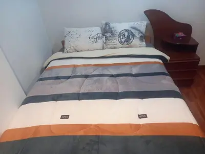a bedroom with a bed with a wooden headboard at Habitación en Cusco in Cusco