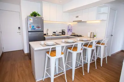 a kitchen with a white island with bar stools at BSR Modern Spacious New Flat in Miraflores w/ Pool in Lima