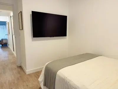 a bedroom with a bed and a flat screen tv on the wall at New 2D gym-grill Miraflores 1 block Malecón in Lima
