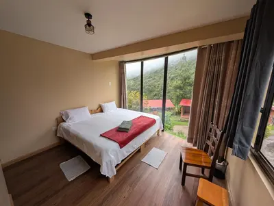 a bedroom with a bed and a large window at TUMI Specialty Travel in Colcapampa