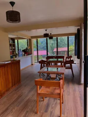 a living room with wooden tables and windows at TUMI Specialty Travel in Colcapampa