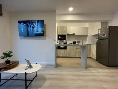 a living room with a kitchen with a tv on the wall at Departamento con baño y cocina equipada in Lima