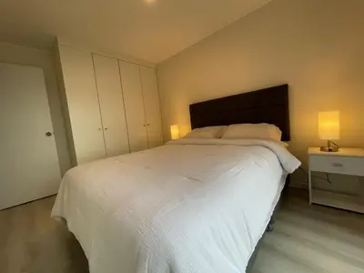 a bedroom with a large white bed and two lamps at Departamento con baño y cocina equipada in Lima