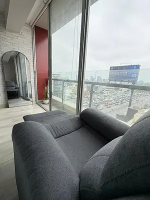 a living room with a couch and a large window at Acogedor Loft con ubicación céntrica en Lima in San Antonio