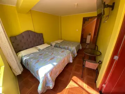 a bedroom with two beds and a table in it at Churin Hostal J&D in Churín