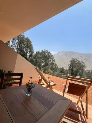 a wooden table with a vase of flowers on a balcony at Rosa Estela in Cieneguilla