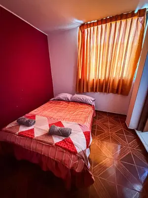 a bedroom with a bed with a red wall at Hospedaje Arco Real in Ica
