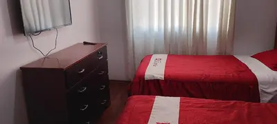 a bedroom with two beds and a dresser and a television at Hotel D'Gloria Churin in Churín