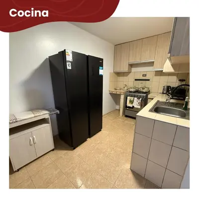 a kitchen with a black refrigerator and a sink at Departamentos Sumaq Plaza - Bellido in Ayacucho