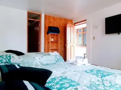 a bedroom with two beds and a flat screen tv at La casa de Cuni in Oxapampa