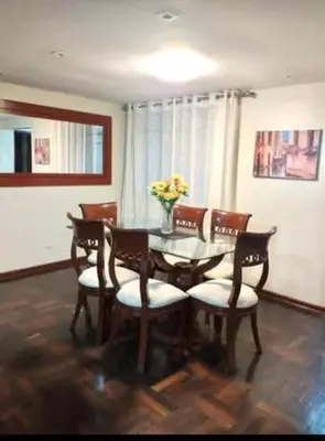 a dining room table with chairs and a vase of flowers at Duplex en San Borja in Lima