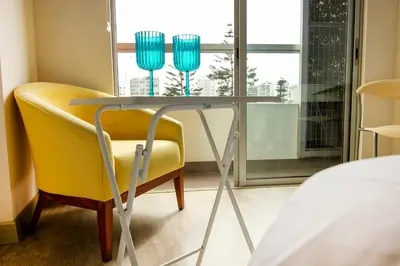 a table and a yellow chair in a room with a window at View & Pool Barranco loft G15 in Lima
