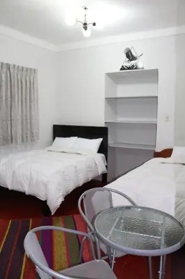 a room with two beds and a table and chairs at Apartamento Privado en San Pedro Cusco in Cusco
