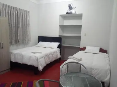 a bedroom with two beds and a chair in it at Apartamento Privado en San Pedro Cusco in Cusco